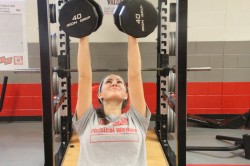 Senior Emily English presses 40-pound dumb bells during Varsity P.E. English plays volleyball. PHOTO by Rachael Kossy