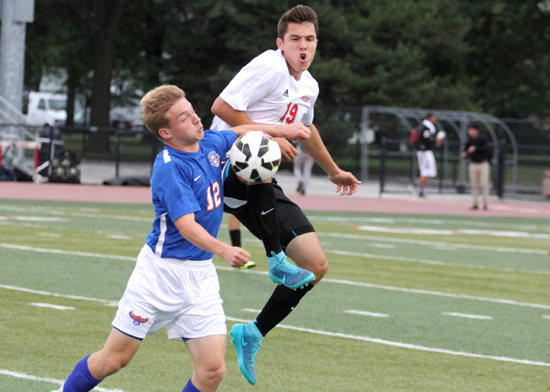 Junior Alen Radeljic attempts to steal the ball midair from Hoffman Estates midfielder. Photo By Emily Butera