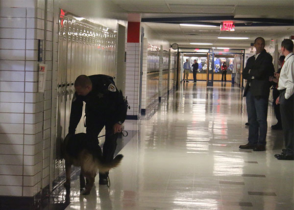 Skokie Police Offcier, Nick Larson, guides canine down the wall of lockers. Photo by Emily Butera