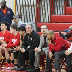 Boys' basketball head coach Bob Williams sits on the bench with his players as he coaches his final game against Evanston Tuesday, Feb. 28. Williams, who was placed on administrative leave earlier this week and is now back to his duties, is set to retire at the end of school year. Photo by Sana Kadir